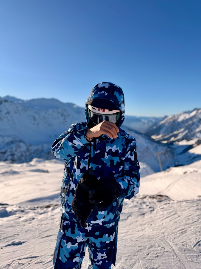 A skier in a blue camo suit on a snowy mountain
